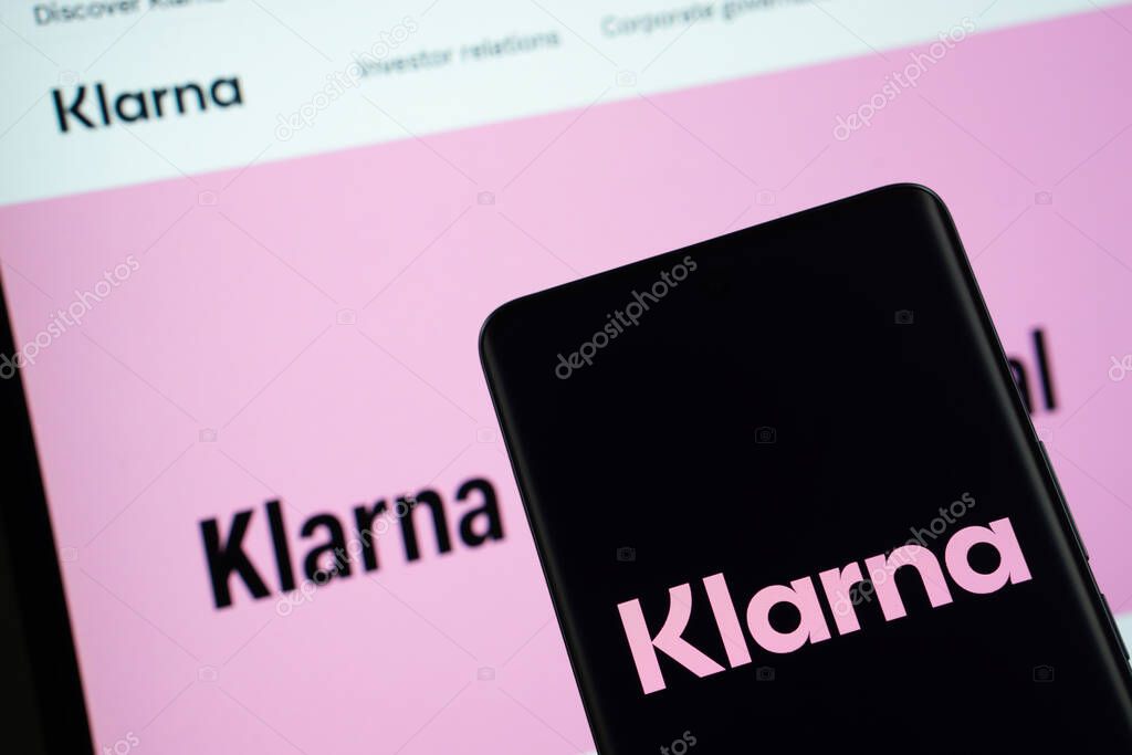 Dhaka, Bangladesh - 17 March 2025: The logo of the klarna is displayed on a smartphone screen, and the website klarna is visible on a computer screen in the background.