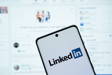 Dhaka, Bangladeş - 17 Mart 2025: Bağlantının logosu akıllı telefon ekranında gösteriliyor ve bağlı olduğu web sitesi arka plandaki bilgisayar ekranında görülebiliyor.