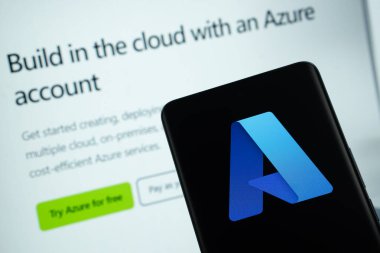 Dhaka, Bangladeş - 17 Mart 2025: Mikrosoft gök mavisi logosu bir akıllı telefon ekranında gösteriliyor ve mikrosoft gök mavisi arka plandaki bilgisayar ekranında görülebiliyor.