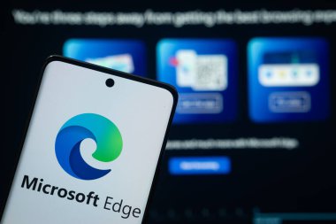 Dhaka, Bangladeş - 17 Mart 2025: Mikrosoft kenarının logosu akıllı telefon ekranında gösteriliyor ve mikrosoft web sitesi arka planda bir bilgisayar ekranında görülebiliyor.