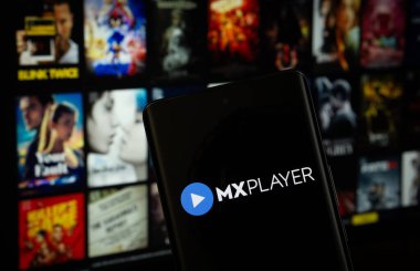 Dhaka, Bangladeş - 17 Mart 2025: MX oynatıcının logosu akıllı telefon ekranında gösteriliyor ve mx oynatıcı web sitesi arka planda bir bilgisayar ekranında görülebiliyor.