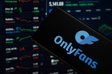 Dhaka, Bangladeş - 17 Mart 2025: Sadece hayranların logosu bir akıllı telefon ekranında görüntülenir, arka planda bilgisayar ekranında bir stok grafik web sayfası görünür..