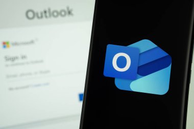 Dhaka, Bangladeş - 17 Mart 2025: Mikrosoft görünüm logosu bir akıllı telefon ekranında sergilenmektedir, arkaplanda bir bilgisayar ekranında bir stok grafik web sayfası görünür.