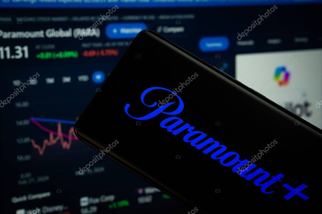 Dhaka, Bangladesh- 17 March 2025: paramount+ logo is displayed on a smartphone screen, with a stock graph webpage visible on a computer screen in the background.