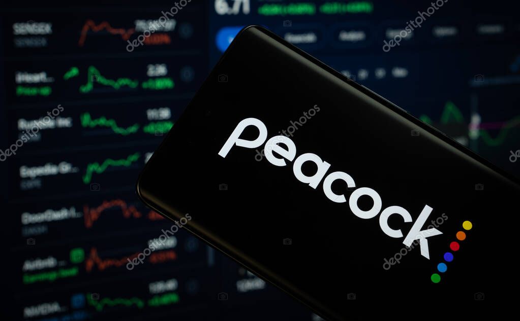 Dhaka, Bangladesh- 17 March 2025: peacock logo is displayed on a smartphone screen, with a stock graph webpage visible on a computer screen in the background.