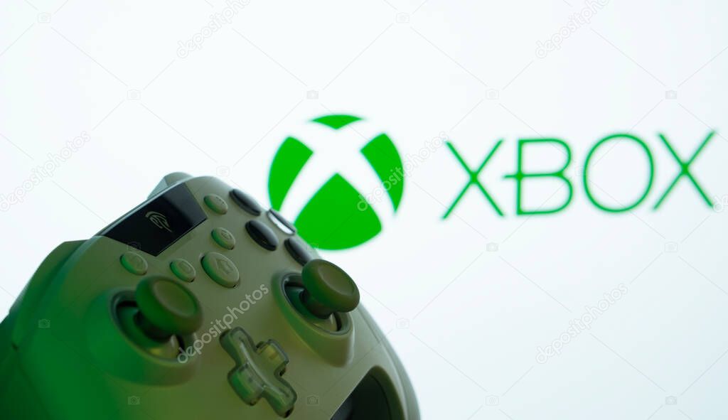 Dhaka, Bangladesh- 09 May 2025: A close-up of a white gamepad with the XBOX seen on screen in the background.