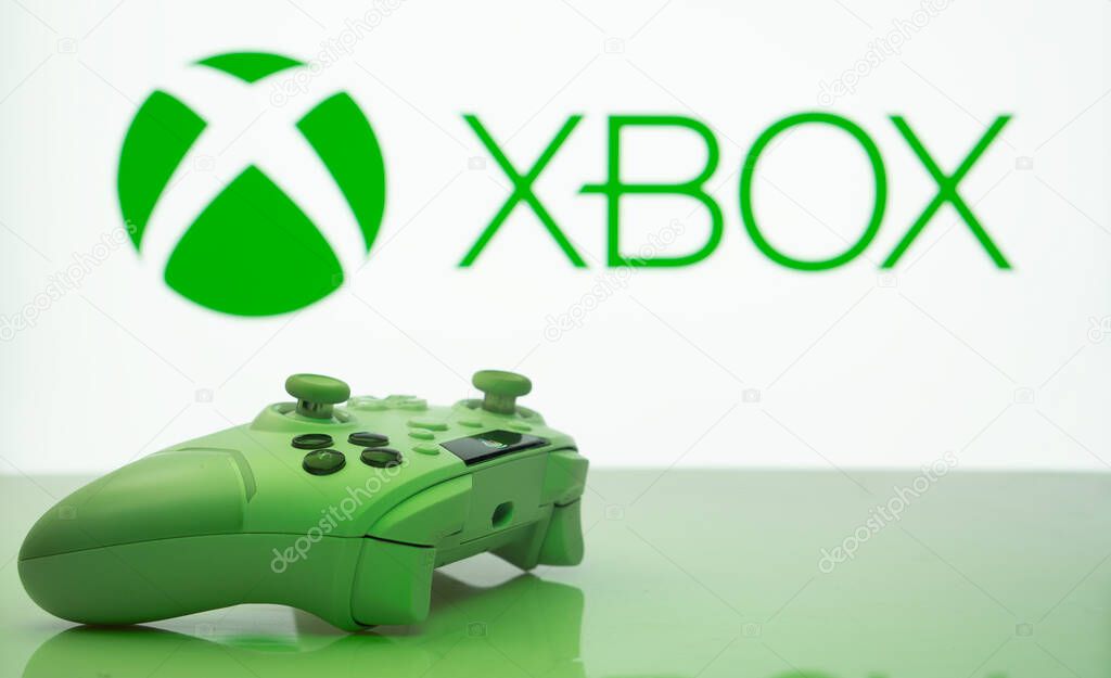 Dhaka, Bangladesh- 09 May 2025: A close-up of a white gamepad with the XBOX seen on screen in the background.