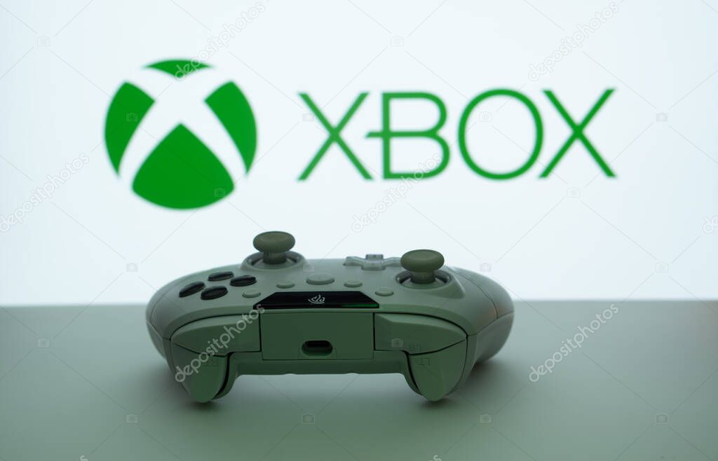 Dhaka, Bangladesh- 09 May 2025: A close-up of a white gamepad with the XBOX seen on screen in the background.