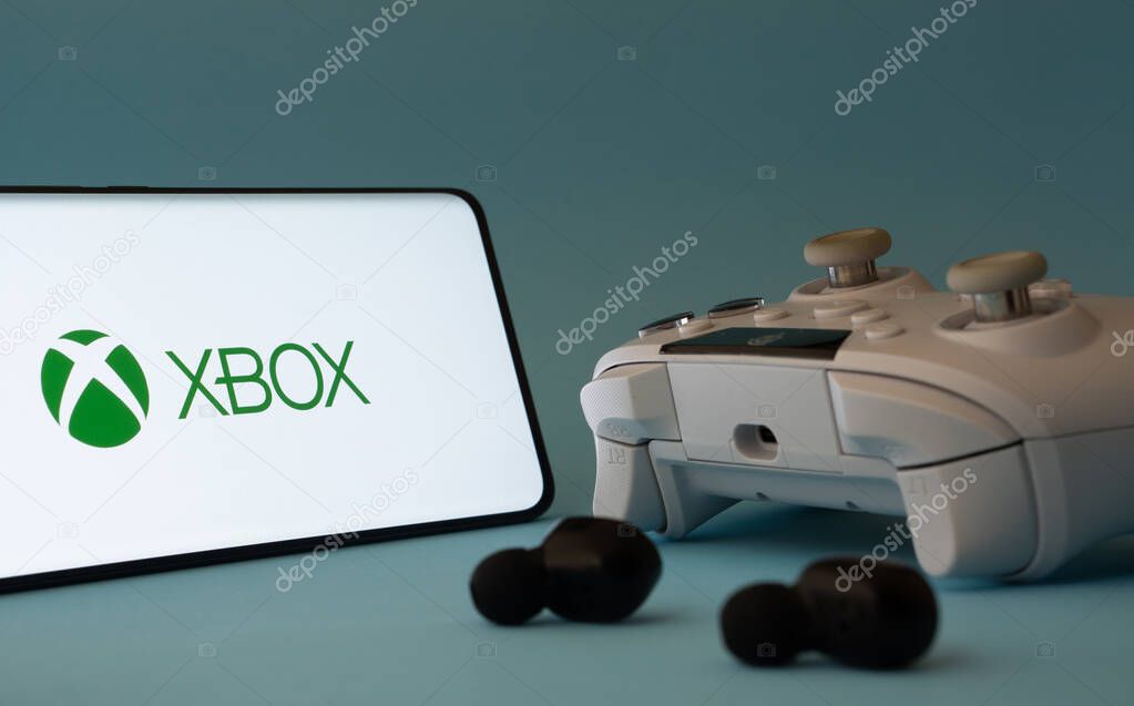 Dhaka, Bangladesh- 09 May 2025: A close-up of a white gamepad with the XBOX seen on smartphone screen in the background.