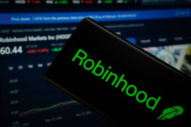 Dhaka, Bangladeş - 18 Mart 2025: Robinhood logosu bir akıllı telefon ekranında sergilenmektedir, arka planda bir bilgisayar ekranında bir stok grafik web sayfası görünür.