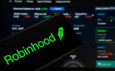 Dhaka, Bangladeş - 18 Mart 2025: Robinhood logosu bir akıllı telefon ekranında sergilenmektedir, arka planda bir bilgisayar ekranında bir stok grafik web sayfası görünür.