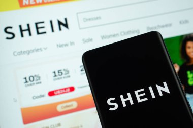 Dhaka, Bangladeş - 18 Mart 2025: Shein logosu akıllı telefon ekranında gösteriliyor ve web sitesi sayfası arka plandaki bilgisayar ekranında görülebiliyor.