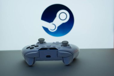 Dhaka, Bangladeş - 03 Haziran 2025: Steam logosu önünde beyaz bir arkaplanda oyun denetleyici.