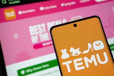 Dhaka, Bangladeş - 18 Mart 2025: Temu logosu akıllı telefon ekranında gösteriliyor ve temu web sitesi arka planda bir bilgisayar ekranında görülebiliyor.