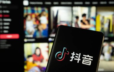 Dhaka, Bangladeş - 18 Mart 2025: Tiktok logosu akıllı telefon ekranında gösteriliyor ve tiktok web sitesi arka plandaki bilgisayar ekranında görülebiliyor.