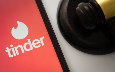 Dhaka, Bangladeş - 18 Mart 2025: Bir hakimin tokmağının yanında Tinder uygulamasını gösteren iPad ekranının yakın çekimi.