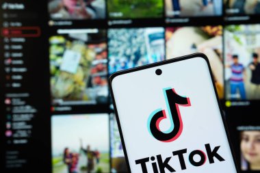 Dhaka, Bangladeş - 18 Mart 2025: Tiktok logosu akıllı telefon ekranında gösteriliyor ve tiktok web sitesi arka plandaki bilgisayar ekranında görülebiliyor.