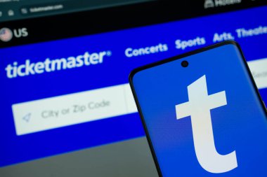 Dhaka, Bangladeş - 18 Mart 2025: Ticketmaster 'ın logosu akıllı telefon ekranında gösteriliyor ve Ticketmaster sitesi arka plandaki bilgisayar ekranında görülebiliyor.