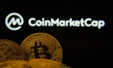 Dhaka, Bangladeş - 27 Mart 2025: Bitcoin sikkelerine yakın plan arkaplanda bir ekranda Coinmarket logosu görünür.