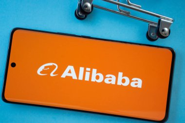 Dhaka, Bangladeş - 03 Temmuz 2025: Alibaba logosunu mavi arka planda alışveriş arabası tekerlekleri ile gösteren akıllı telefon ekranı.