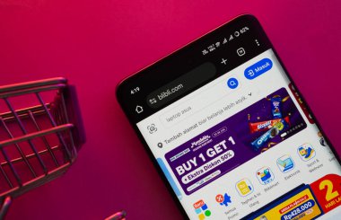 Dhaka, Bangladeş - 23 Haziran 2025: Canlı bir arka planda Blibli web sitesini alışveriş arabasıyla gösteren bir akıllı telefon gösterildi.