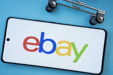 Dhaka, Bangladeş - 03 Temmuz 2025: Akıllı telefon ekranı eBay logosunu mavi arka planda alışveriş arabası tekerlekleri ile gösteriyor.