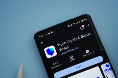 Dhaka, Bangladesh- 30 Sep 2025: On a blue surface, a smartphone displays the Trust Wallet app within the Google Play Store.