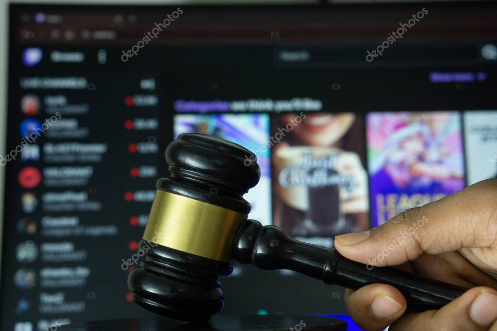 Dhaka, Bangladesh- 30 Sep 2025: A hand holds a gavel in front of a computer screen displaying Twitch website