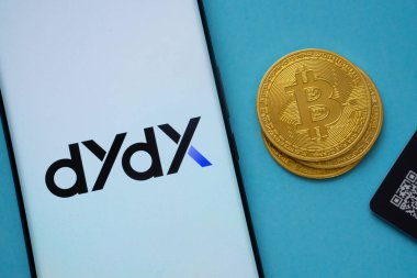 Dhaka, Bangladesh- 03 Oct 2025: Dydx logo on smartphone screen near Bitcoin coin and QR code on blue background.