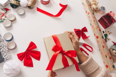 Beyaz arka planda kırmızı kurdeleli altın kutuları olan bir kız ya da yeni yıl hediyeleri. Mutlu Noeller, el yapımı, aile kutlaması