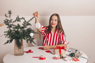 Güzel bir kız köknar dallarını kağıt oyuncaklarla süslüyor. Noel ve Yeni Yıl 'ı kutlamak, ekolojik tüketim, el yapımı