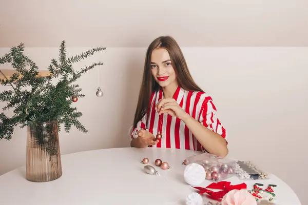 Güzel bir kız kozalaklı dalları yeniden kullanılabilir plastik oyuncaklarla süslüyor. Noel ve Yeni Yıl kutlamaları, ekolojik tüketim