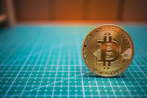 Yeşil bir ızgara yüzeyinde duran Altın Bitcoin, dijital para birimini ve engelleme teknolojisini temsil ediyor, finansal veya teknolojik temalar için mükemmel.
