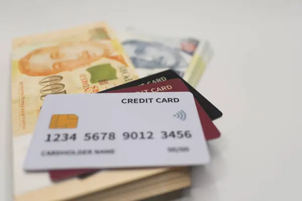 Beyaz kredi kartı Singapur dolar banknotları yığını üzerine yerleştirilmiş, modern finans, nakitsiz işlemler ve dijital ödeme çözümlerini sembolize ediyor .