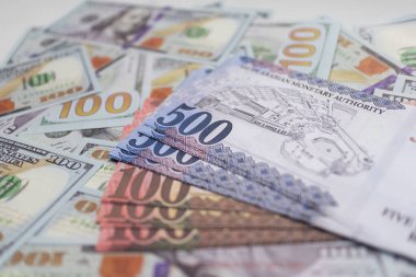 Mavi ve Kahverengi Riyal banknotları, uluslararası finans, döviz ve küresel ticaret birimlerini temsil eden Amerikan dolarlarının üstüne istiflenmiştir..