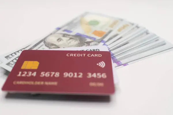 Kestane rengi kredi kartı bir yığın mavi ve altın üzerine yerleştirilmiş Amerikan doları banknotları, nakit ödemeler, finans ve Amerikan para birimi işlemlerini sembolize ediyor .