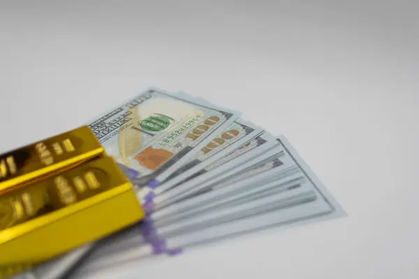 Cilalanmış altın külçeleri, finansal büyüme, prim yatırımları ve lüks varlıkları temsil eden bir yığın mavi ve altın Amerikan dolarının üzerinde dinleniyor..