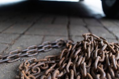 Paslı zincirler çimento yüzeyinde birbirine dolanmış. Güçlü ve kırsal bir estetik sunuyor..