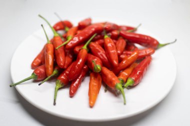 Beyaz bir tabakta sergilenen taze kırmızı biber yığını..