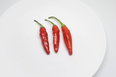 Arka planda sergilenen üç taze kırmızı biber..