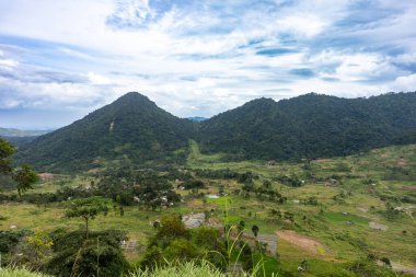 Yeşil dağları olan yeşil bir manzara, doğanın güzelliğini ve sakin kırsal manzarasını gözler önüne seriyor..