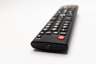 Beyaz arkaplan üzerine vurgulanmış düğmeleri olan siyah bir TV uzaktan kumandasının görünümünü kapat, elektronik ve ev aletleriyle ilgili temalar için ideal.