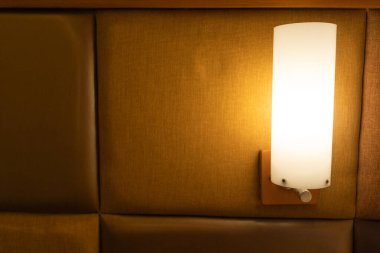 Yumuşak, parlak bir duvar lambası dokulu, kahverengi bir zemin üzerinde, sıcak bir iç mekan titreşimi yaratıyor..