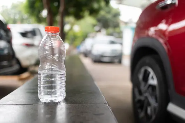 Turuncu kapaklı plastik su şişesi, şehir arka planına sahip bir çıkıntıya yerleştirilmiş..