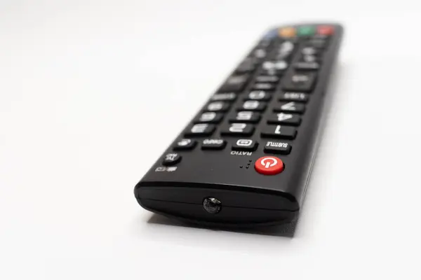 Beyaz arkaplan üzerine vurgulanmış düğmeleri olan siyah bir TV uzaktan kumandasının görünümünü kapat, elektronik ve ev aletleriyle ilgili temalar için ideal.