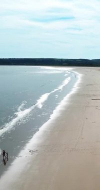 Tor Bay Plajı 'ndaki dalgalar the 124; 124plaj boyunca insansız hava aracı panoraması; güneşli bir yaz günü, plajdaki insanlar (124); Galler Birleşik Devletleri (124); hava aracı görüntüler dikey