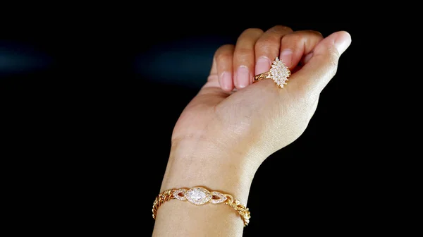 ブラックの背景を持つあなたのデザインのニーズに最適な女性の手に設定された金の宝石のブレスレットと輝く宝石リング — ストック写真