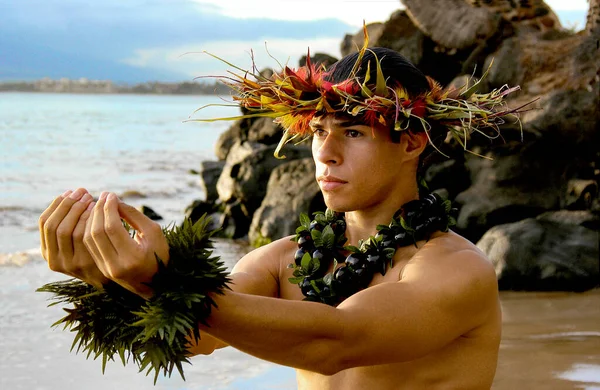 Male Hula Dancer poses on the beach in a hula dance offering pose.