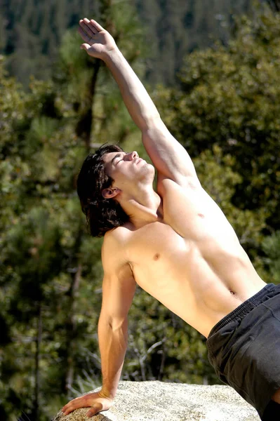 年轻的不穿运动衫的男子体操运动员正在伸展和炫耀他的肌肉 — 图库照片