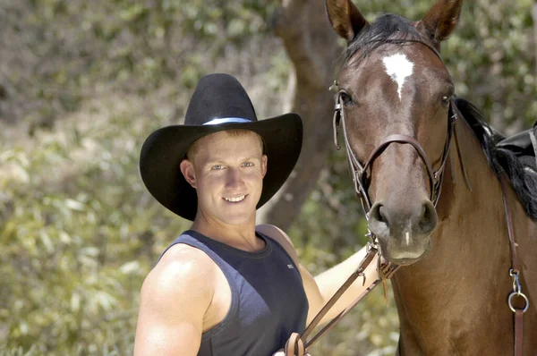 A portrait shot of a cowboy with his horse.